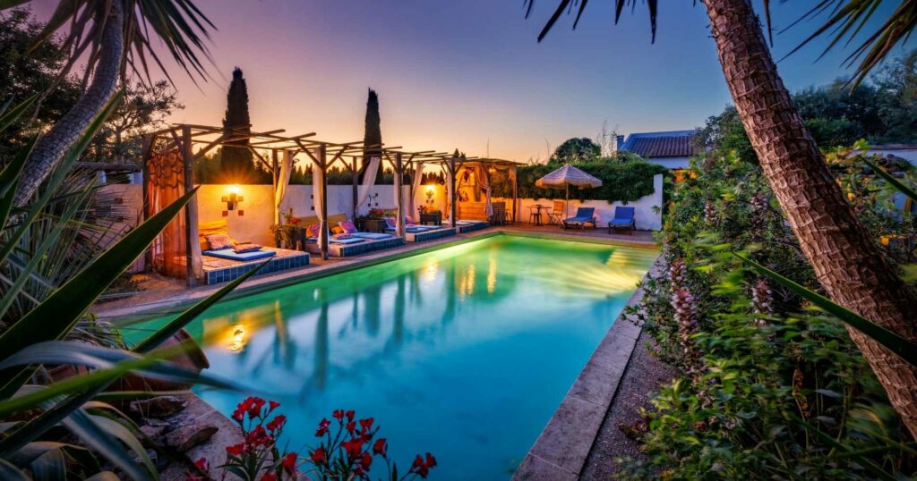 Piscine éclairée au crépuscule d'un domaine équestre à Vestric-et-Candiac, photographie immobilière de prestige