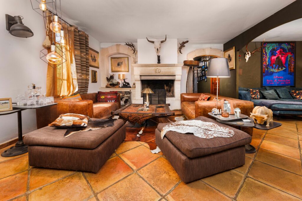 Photographe immobilier de prestige : salon à cheminée avec canapés en cuir et tomettes en flambient, domaine à Vestric-et-Candiac