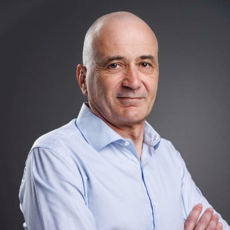 Portrait de dirigeant de Fred R. en chemise bleu clair, bras croisés, sur fond gris