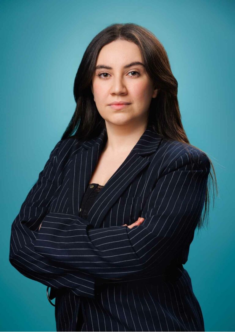 Portrait corporate d’une dirigeante d’entreprise bras croisés, en studio sur fond turquoise