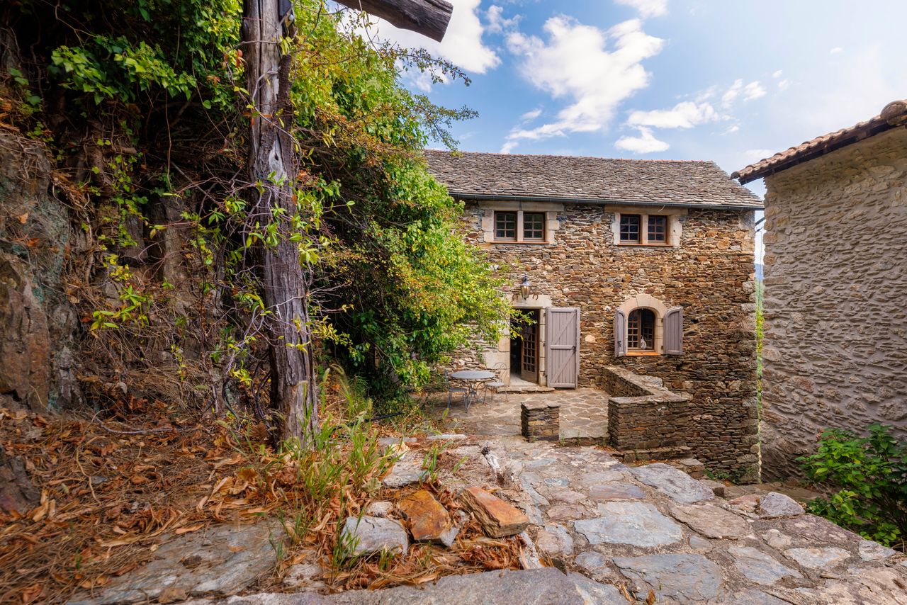 Cour pavée de pierre entre deux bâtisses en schiste d'un domaine des Cévennes