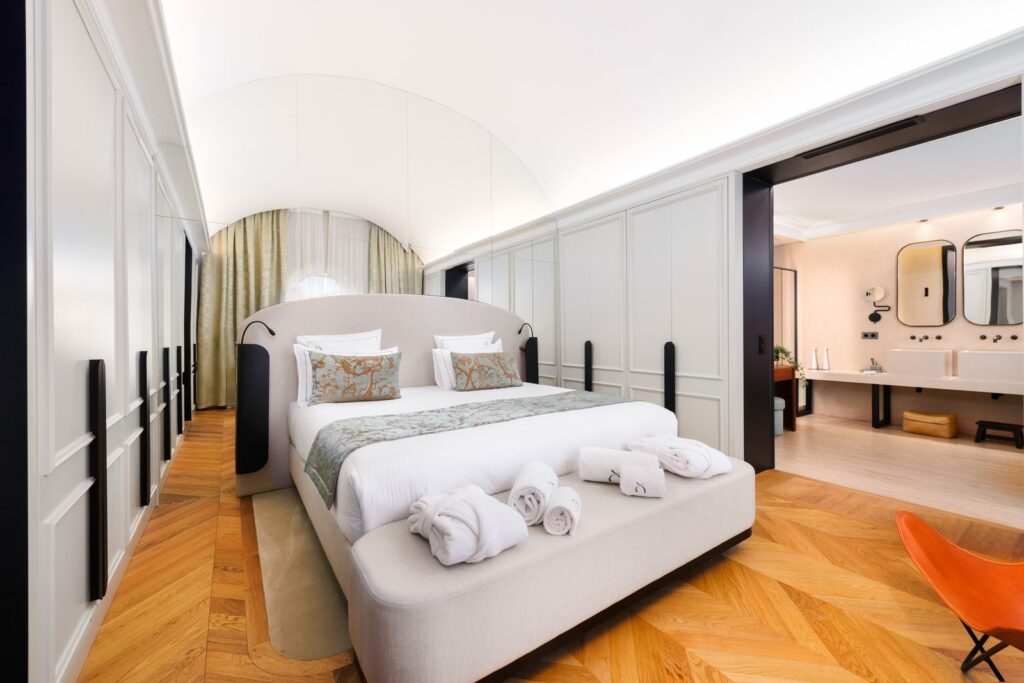 Chambre du château Pimo avec lit capitonné, parquet en point de Hongrie et salle de bain ouverte
