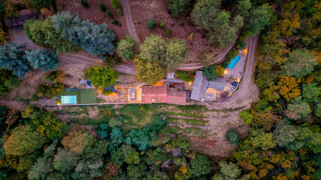 Vue aérienne d’un domaine en pierre avec piscine au milieu des arbres, Génolhac