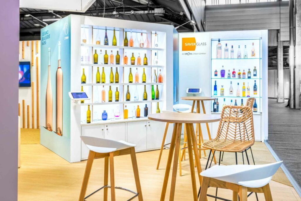 Bar du stand Saverglass au salon SITEVI avec vitrines de bouteilles rétroéclairées et chaises en rotin
