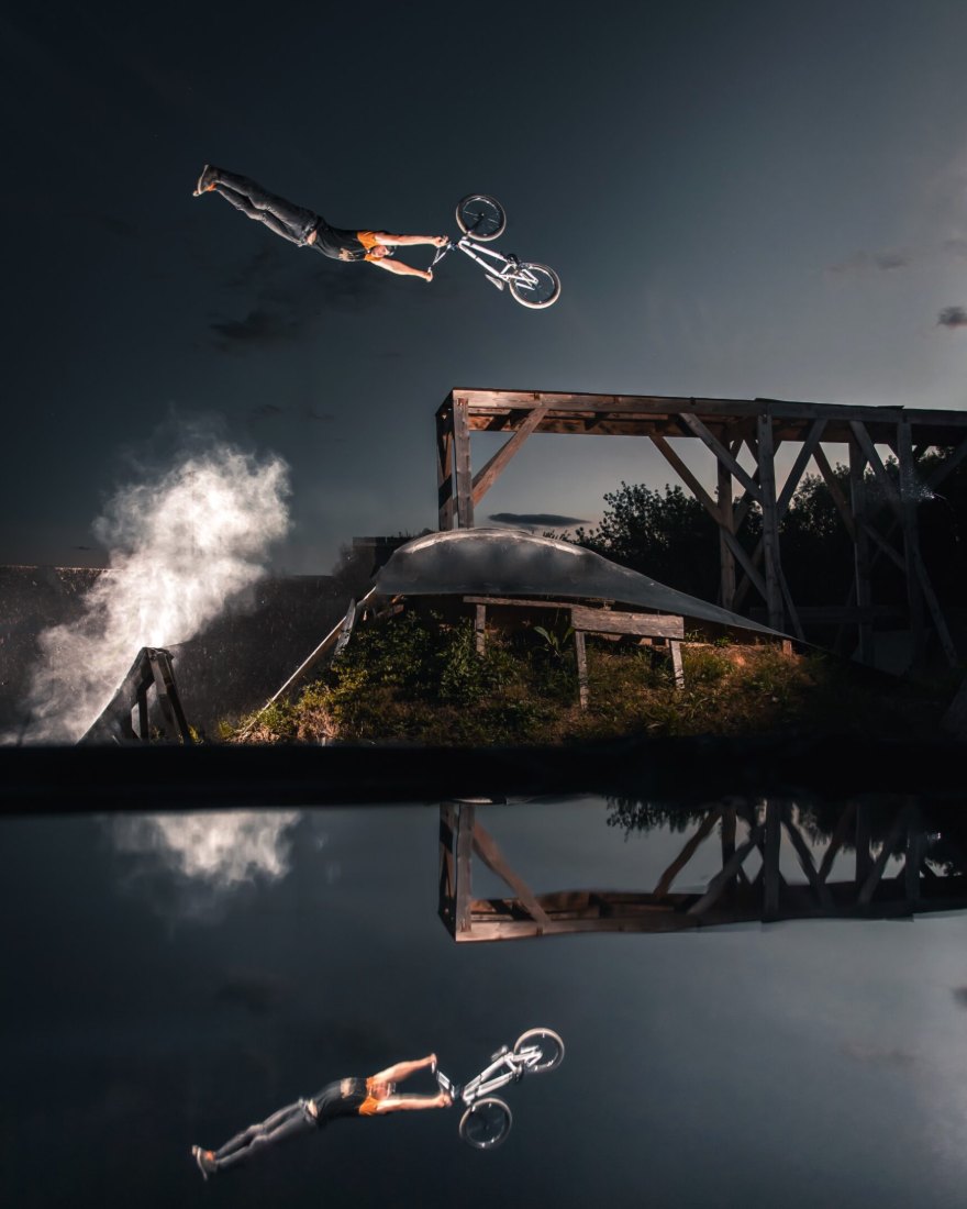 Pierre Colsenet en saut de BMX à la tombée de la nuit, reflété dans l'eau
